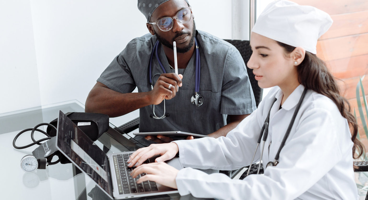 Two healthcare professionals reviewing information with a laptop and tablet.